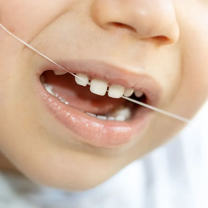 Child learning to floss teeth